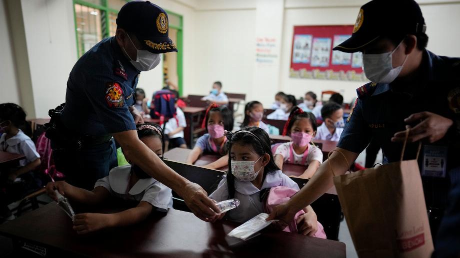 La police distribue de l'alcool et des masques faciaux aux élèves lors de l'ouverture des classes à l'école primaire San Juan dans le métro de Manille, aux Philippines, le lundi 22 août 2022. (AP Photo/Aaron Favila)