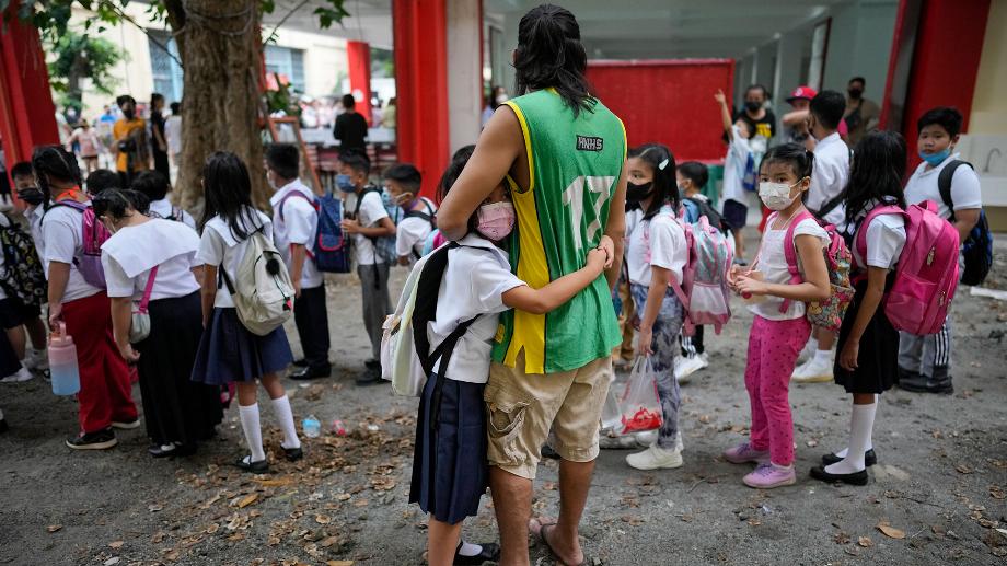 Une fille tient son père dans ses bras lors de l'ouverture des classes à l'école élémentaire San Juan de la région métropolitaine de Manille, aux Philippines, le lundi 22 août 2022. (AP Photo/Aaron Favila)