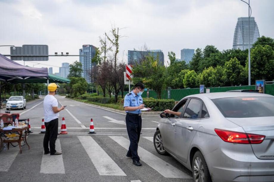Un policier inspectant une voiture à l'extérieur d'une section bloquée de l'avenue Jinjiang lors d'un verrouillage pour lutter contre le COVID-19 à Chengdu (Reuters)