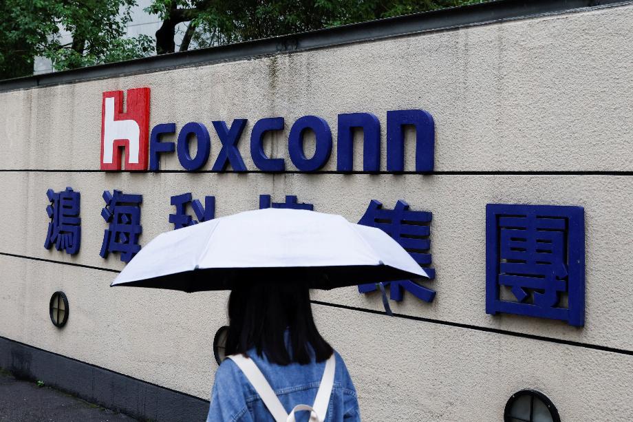 Une femme portant un parapluie passe devant un logo Foxconn devant un bâtiment d'entreprise à Taipei, Taïwan, le 31 octobre 2022. REUTERS/Carlos Garcia Rawlins