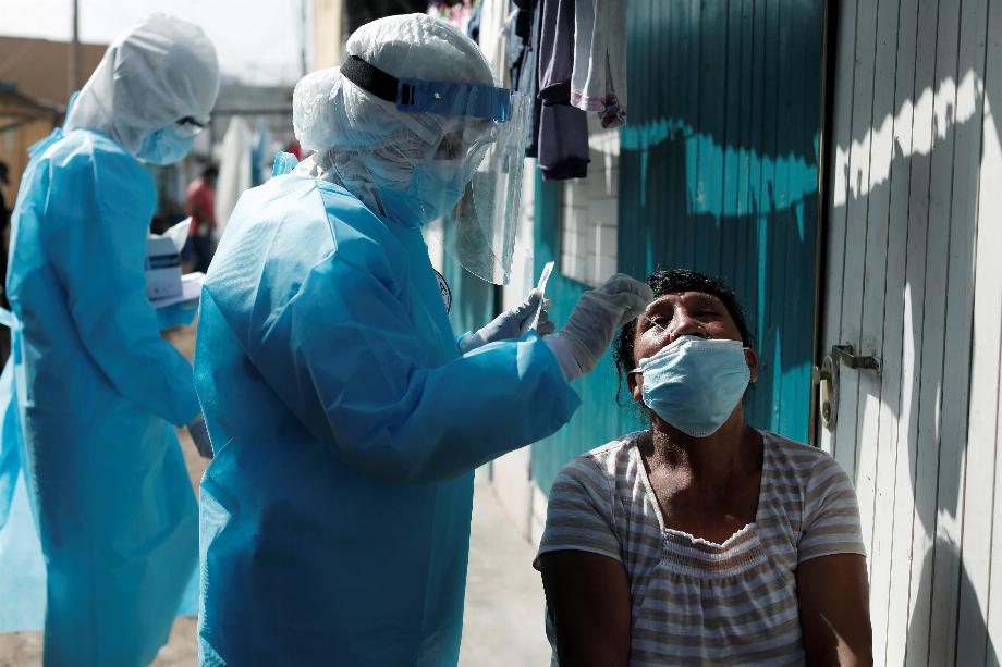 Un travailleur de la santé portant un équipement de protection individuelle (EPI) prélève un échantillon d'écouvillon d'une femme pour le test de la maladie à coronavirus (COVID-19) à Cantagallo, une communauté indigène Shipibo-Conibo, lors de la campagne de vaccination contre le coronavirus, à Lima, Pérou Février 19, 2021. REUTERS/Angela Ponce
