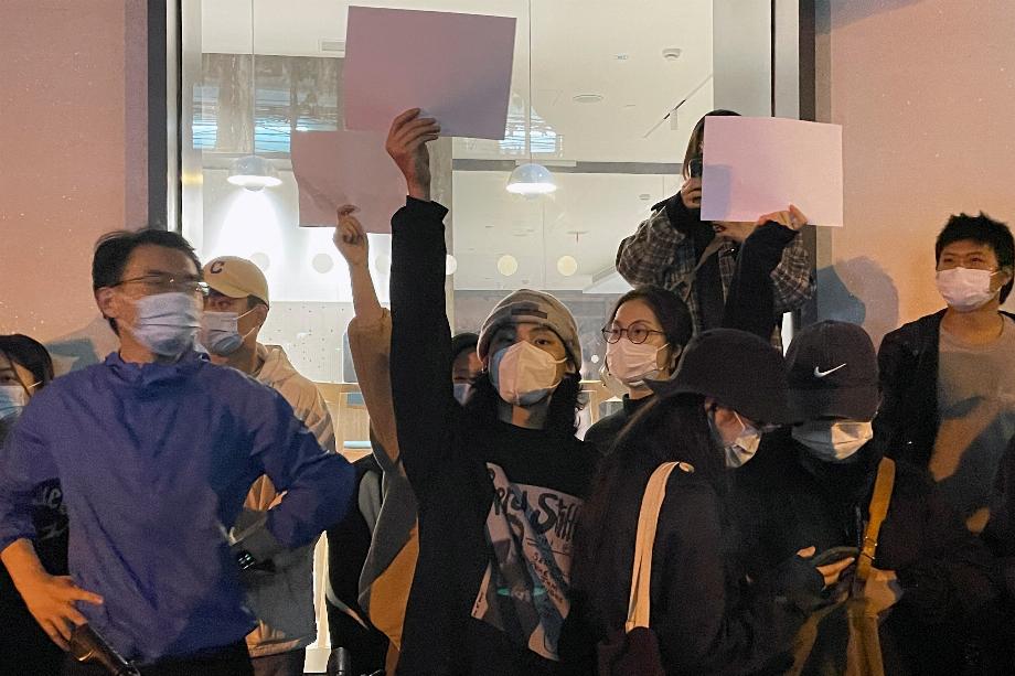 Des gens tiennent des feuilles de papier vierges lors d'une manifestation contre les restrictions du COVID-19 à la suite de l'incendie meurtrier d'Urumqi, à Shanghai, en Chine, le 27 novembre 2022. (REUTERS/Josh Horwitz)