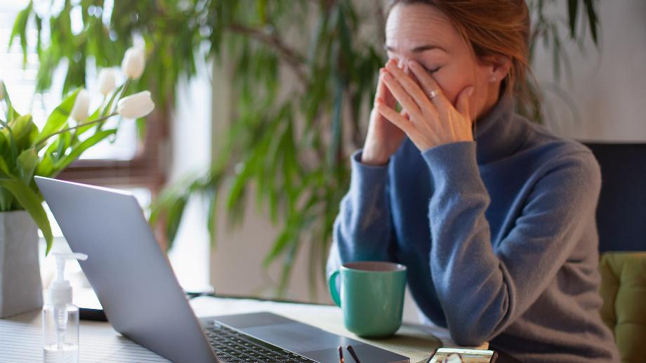 Femme se frottant les yeux devant un ordinateur portable. Travailler au bureau à domicile pendant le verrouillage de Covid-19.