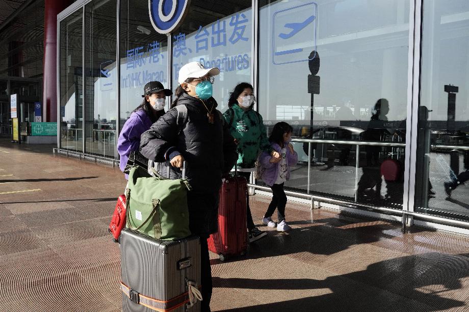 Un groupe de passagers, portant des masques faciaux pour se protéger du coronavirus, à l'aéroport de Pékin