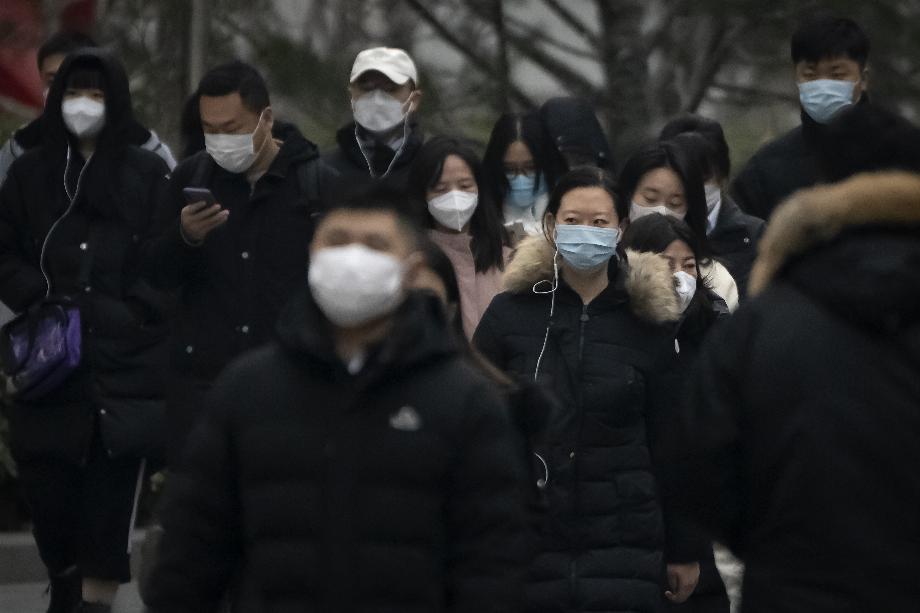 Des piétons portant des masques faciaux marchent dans une rue d'un quartier d'affaires du centre-ville de Pékin, en Chine, le 12 janvier 2023. (AP Photo/Mark Schiefelbein)