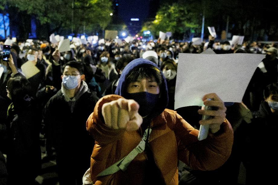 Les gens tiennent des feuilles de papier blanches pour protester contre les restrictions de la maladie à coronavirus (COVID-19), après une veillée pour les victimes d'un incendie à Urumqi, alors que les épidémies de COVID-19 se poursuivent, à Pékin