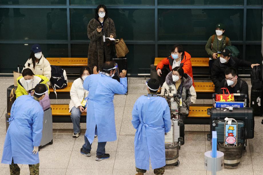 Des soldats en tenue de protection accueillent un groupe de touristes chinois à l'aéroport d'Incheon en Corée du Sud (Reuters)