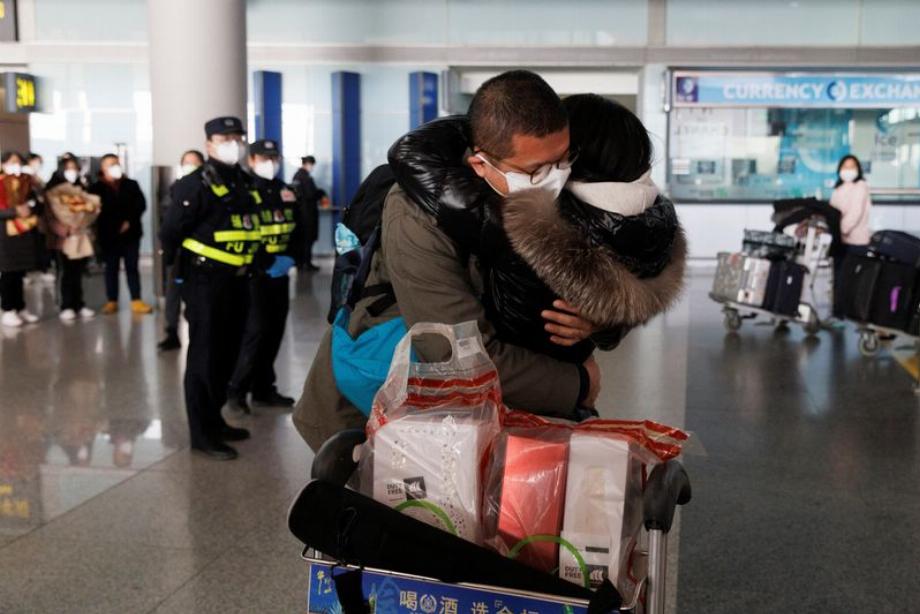 Les gens s'embrassent à la porte des arrivées internationales de l'aéroport international de Pékin (Reuters)