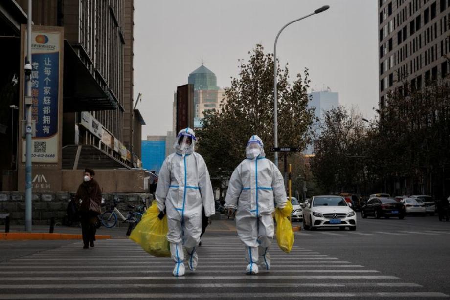 PHOTO DE FICHIER. Des agents de prévention en tenue de protection traversent une rue alors que les épidémies de coronavirus (COVID-19) se poursuivent à Pékin, en Chine. 9 décembre 2022. REUTERS/Thomas Peter