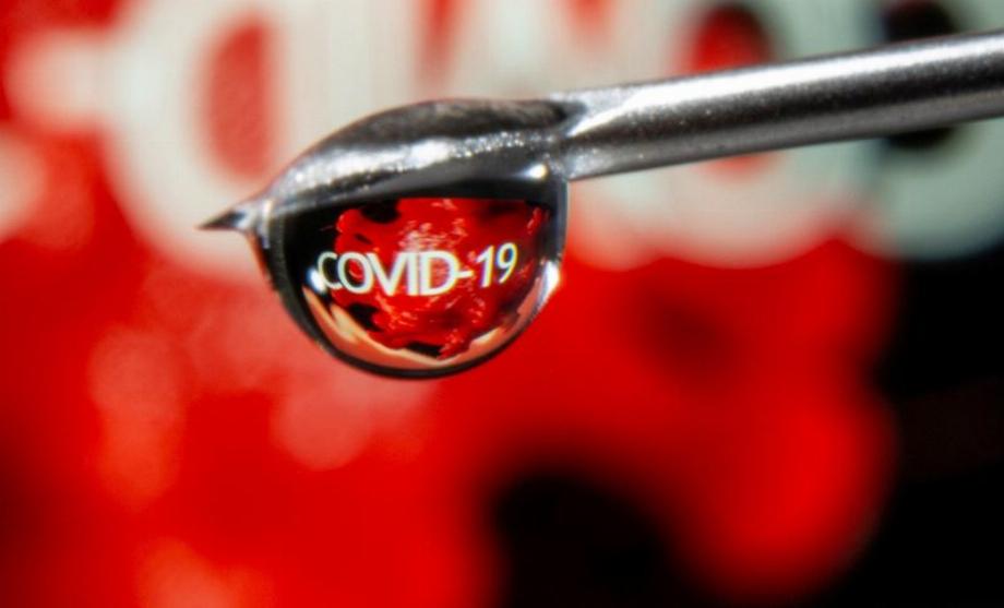 PHOTO DE DOSSIER : Le mot « COVID-19 » se reflète dans une goutte provenant d'une aiguille de seringue. REUTERS/Dado Ruvic/Illustration/Photo d'archives