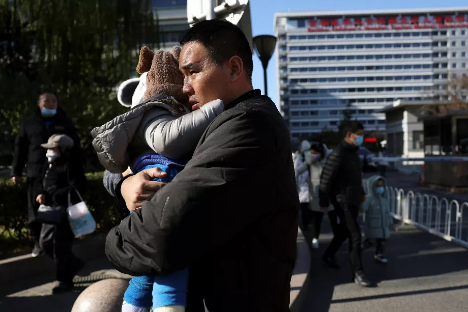 Un homme porte un enfant devant un hôpital pour enfants à Pékin, en Chine, le 24 novembre 2023 (REUTERS/Florence Lo)
